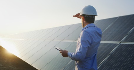 Wall Mural - an young engineer is checking with tablet an operation of sun and cleanliness on field of photovolta