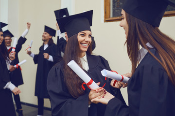 Wall Mural - Female graduates with diplomas in their hands hugging