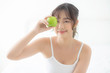 © NT_studio - Beautiful portrait young asian woman holding and eating green apple fruit in the bedroom at home, lifestyle of nutrition girl healthy and care weight loss, health and wellness concept.