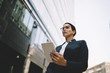 © BullRun - Thoughtful businesswoman watching tablet in urban street