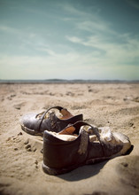 A Lonely Forgotten Pair Of Childs Shoes Discarded In A Beach Or Desert Landscape. Lost Children, Abandoned And Forgotten. Left Behind In A Desolate Environment.