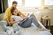 © alfa27 - young caucasian married couple relax at home, enjoy being together, have rest lying on bed and reading a book. leisure time, weekends or holidays. indoors