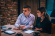 © qunica.com - Young couple drinking coffee and having a business meeting in a cafe