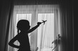 © NATALYA - Silhouette of a happy child girl playing with a toy airplane in her room by the window. Dream to fly. Close the borders of air travel.