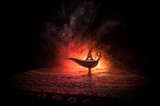 Fototapeta  - Lamp of wishes concept. Antique Aladdin arabian nights genie style oil lamp with soft light white smoke, Dark background.