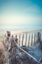 An Old Wooden Fence Near The Sea. It Looks Cold. Sky Is Blue
