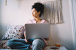 © BullRun - Relaxed ethnic woman browsing laptop and resting at home
