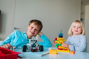 Wall Mural - little girl and boy building robots from colorful plastic blocks