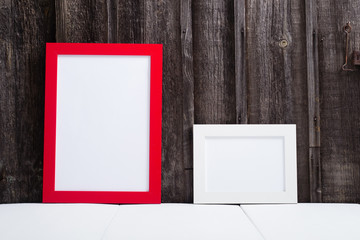 white and red blank picture frames, white table, old wooden wall