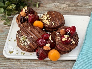 Chocolate pancakes with berries and chocolate, on a plate on a wooden table.