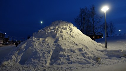 a large snowdrift between two lampposts in the center of Kiruna in Sweden