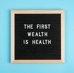 The first wealth is health. Motivational quote on black letter board on blue background. Concept Health Care and Medicine, inspirational quote of the day
