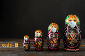 several Russian matryoshka in a mask on a black background, protection from covid-19,