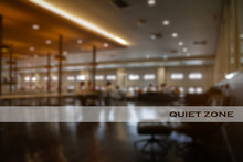 Opaque White Frosted Glass Sticker With Wording “QUIET ZONE” Stick On Clear Mirror And Blurry Group Of People Reading Books In A Public Library Room Background.