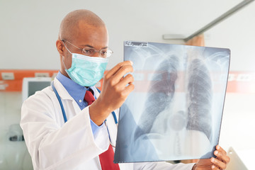 Poster - Doctor wearing a mask while holding a lung radiography