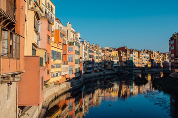 Colorful yellow and orange houses and bridge Pont de Sant Agusti reflected in water river Onyar, in Girona, Catalonia, Spain.