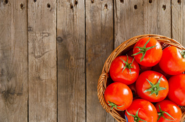 Wall Mural - Wicker basket with tomatoes on an old wooden table.