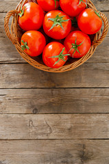 Wall Mural - Wicker basket with tomatoes on an old wooden table.