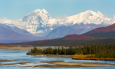 two snow-capped mountains rise above the braided susitna river