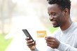 © PheelingsMedia - Black man paying online with credit card on phone