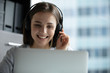 © fizkes - Smiling young woman wearing headset look at laptop screen have fun watching webinar using wireless Internet connection, happy millennial female in headphones work on computer gadget in modern office