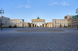 view on the famous Brandenburg gate on the Pariser square in Berlin city, parisian square without tourists and visitors - deserted, blue sky, small clouds