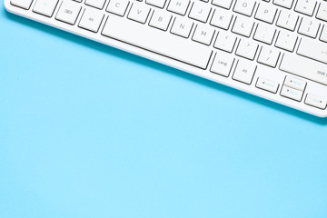 Close up white computer keyboard on blue background. View from above.