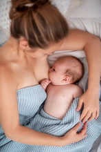 Happy Young Woman Breastfeeding And Hugging Baby. Lactation Newborn Concept.