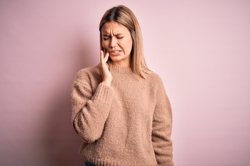 Wall Mural - Young beautiful blonde woman wearing winter wool sweater over pink isolated background touching mouth with hand with painful expression because of toothache or dental illness on teeth. Dentist