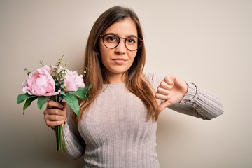 Canvas Print - Young blonde woman holding beautiful romantic floral bouquet over isolated background with angry face, negative sign showing dislike with thumbs down, rejection concept