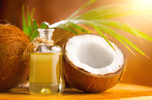 Coconut Palm Oil In A Bottle With Coconuts And Green Palm Tree Leaf On Brown Background. Coco Nut Closeup. Healthy Food, Skin Care Concept. Vegan Food. Skincare Treatments. Aromatherapy.