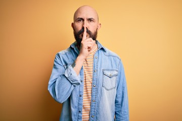 Sticker - Handsome bald man with beard wearing casual denim jacket and striped t-shirt asking to be quiet with finger on lips. Silence and secret concept.