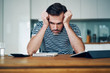© baranq - Depressed man holding head while stressing over money and home finances