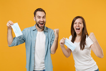 Two people in sterile face masks throw out napkin isolated on yellow background studio. Epidemic pandemic rapidly spreading coronavirus 2019-ncov medicine flu virus ill sick disease treatment concept.