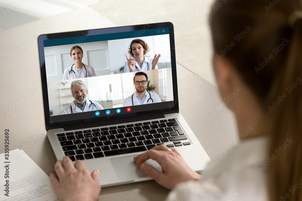 View over client shoulder sit at desk receive medical consultation on-line from diverse specialists. Woman listen doctors about corona virus precautionary measures, videoconference laptop webcam view - obrazy, fototapety, plakaty 
