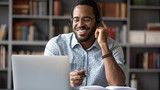 Fototapeta  - Smiling African American man in glasses and headset watch webinar on laptop making notes, happy biracial male student worker in headphones handwriting studying or working using computer