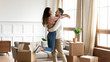 © fizkes - Young man lifting smiling mixed race wife, feeling excited about moving in new house. Happy family couple homeowners celebrating purchasing real estate, having fun in living room, relocation concept.
