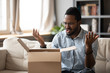 Unhappy African American man client disappointed with product quality shopping online, mad biracial male open cardboard package frustrated with wrong Internet order, bad delivery service concept