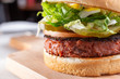 A closeup view of a burger, featuring a burger patty made of plant-based ingredients, in a restaurant or kitchen setting.