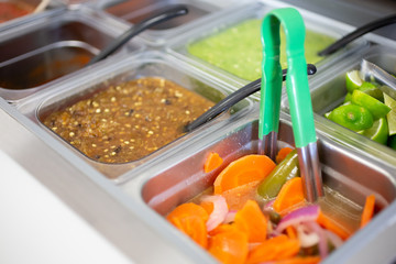 A view of several varieties of Mexican sauces in a salsa bar, in a restaurant setting.