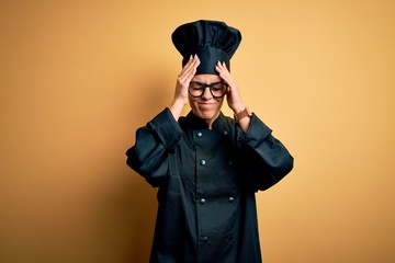 Wall Mural - Young beautiful brunette chef woman wearing cooker uniform and hat over yellow background suffering from headache desperate and stressed because pain and migraine. Hands on head.