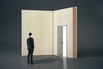 Poster - Businessman looking at abstract open book with door on gray background.