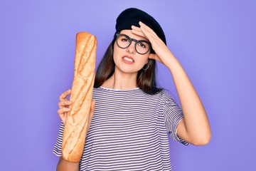 Canvas Print - Young beautiful girl wearing fashion french beret holding fresh baked bread baguette stressed with hand on head, shocked with shame and surprise face, angry and frustrated. Fear and upset for mistake.