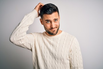 Young handsome man wearing casual sweater standing over isolated white background confuse and wonder about question. Uncertain with doubt, thinking with hand on head. Pensive concept.