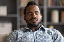 Close up of calm African American young man rest at home daydream or take nap feeling fatigue, exhausted biracial millennial male fall asleep relax in living room, sleeping or taking break