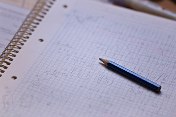 Closeup of a notebook full of mathematical operations next to pencil