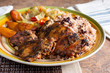 A view of a plate of jerk chicken, in a restaurant or kitchen setting.