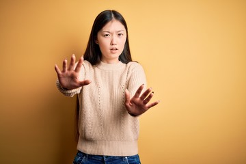 Poster - Young beautiful asian woman wearing casual sweater over yellow isolated background doing stop gesture with hands palms, angry and frustration expression