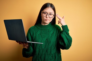 Sticker - Young asian business woman wearing glasses and working using computer laptop Shooting and killing oneself pointing hand and fingers to head like gun, suicide gesture.