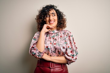 Sticker - Young beautiful curly arab woman wearing floral t-shirt standing over isolated white background with hand on chin thinking about question, pensive expression. Smiling with thoughtful face. Doubt